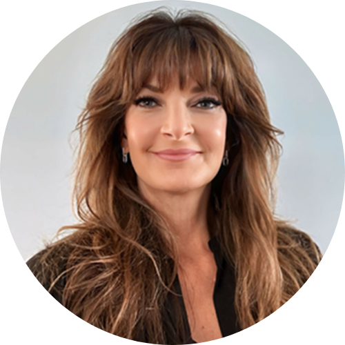 Smiling woman with long brown hair and bangs, wearing a black blouse, facing the camera.