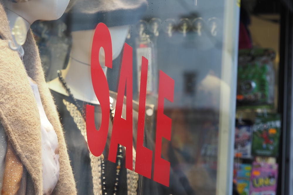 Store displays sale sign in shop window during daytime