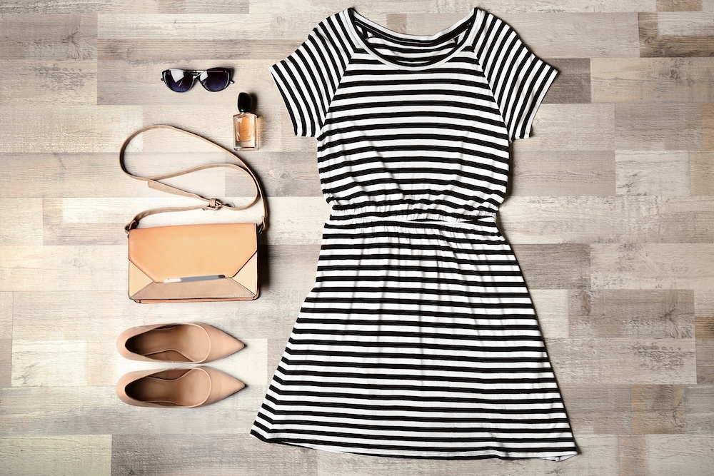 Stylish female clothes with accessories on wooden background