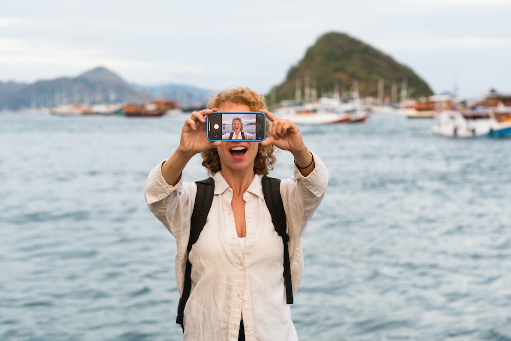 person taking a selfie on vacation in front of a body of water.