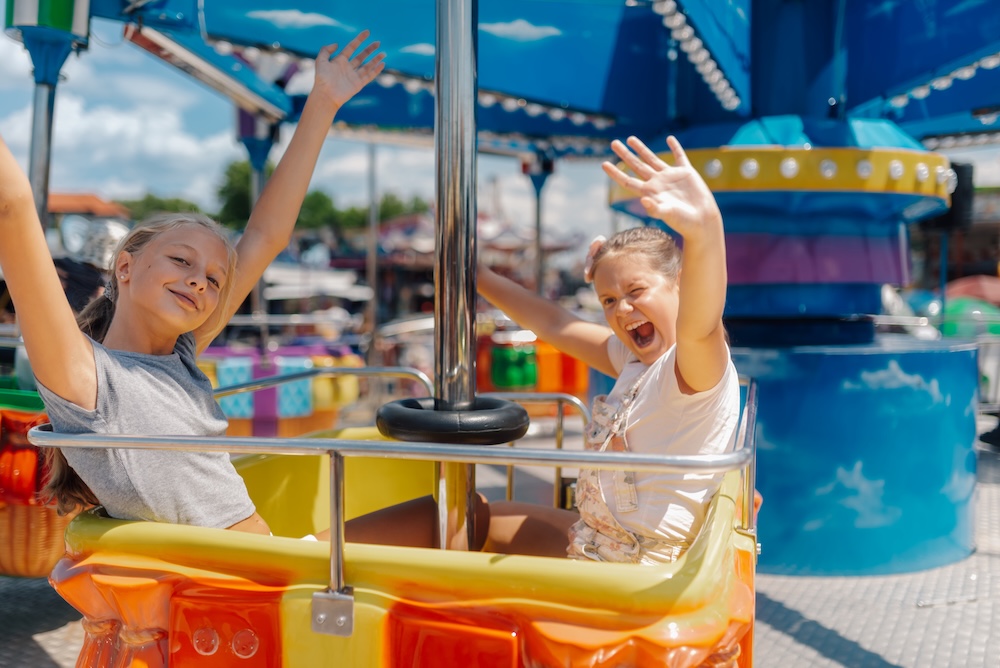 Two young girls enjoying a carousel ride at an amusement park