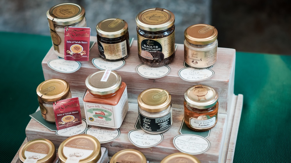 Various jars filled with honey and preserves are arranged on wooden shelves