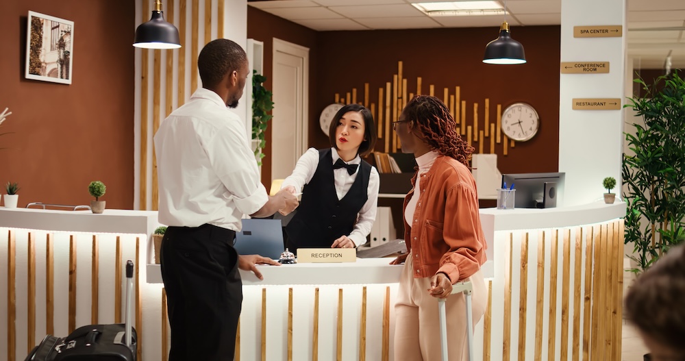 Friendly receptionist offering room key to guests after check in process is finalized.
